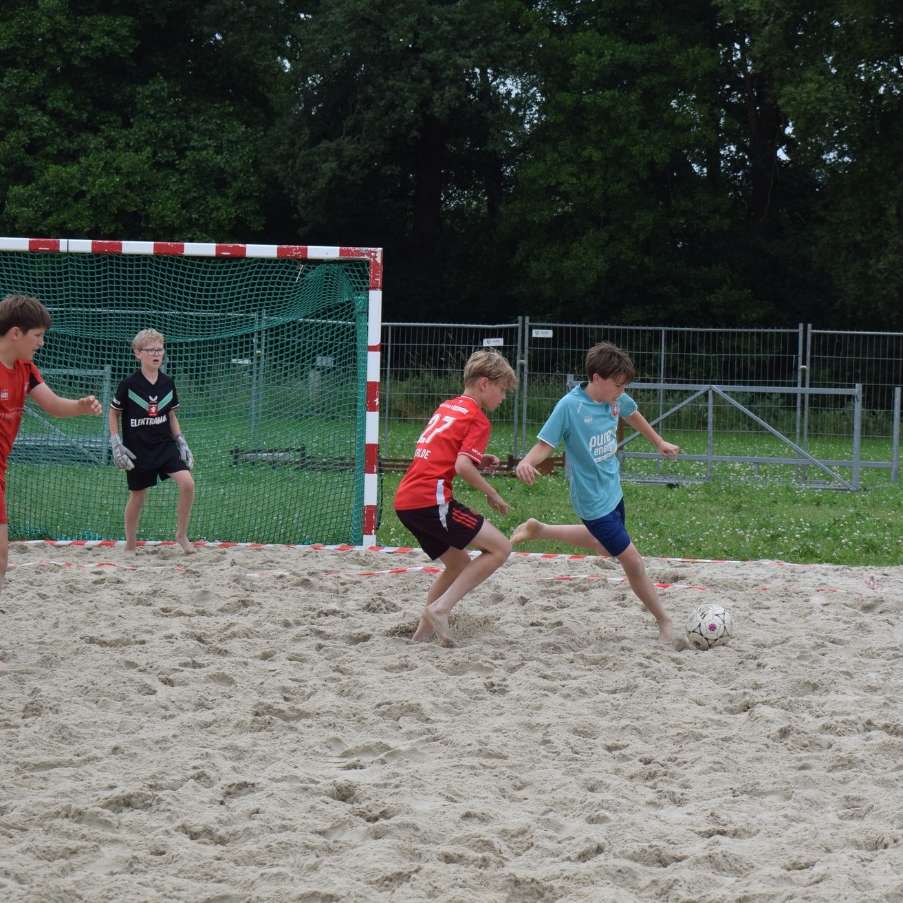 Jeugd aan het beachvoetballen in het zand
